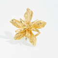 Gold flower-shaped ring on a light gray background